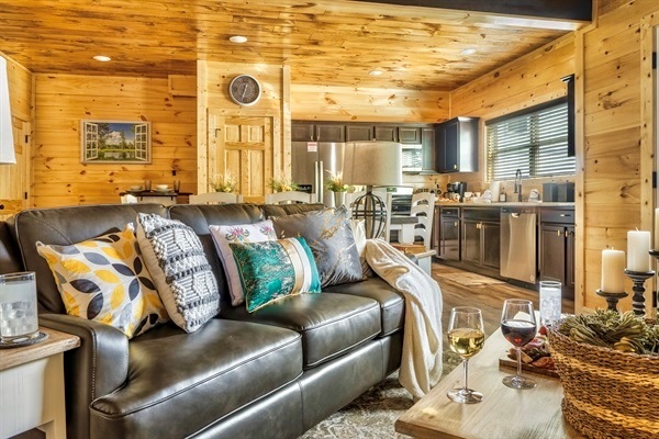 A luxurious living space featuring a spacious, comfortable couch, armchairs, and a 65-inch LED smart TV, surrounded by elegant decor.