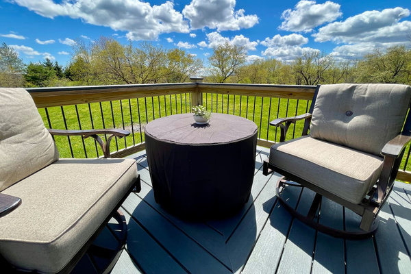 Swivel chairs around propane fire pit on deck overlooking the meadow and pond (not pictured).