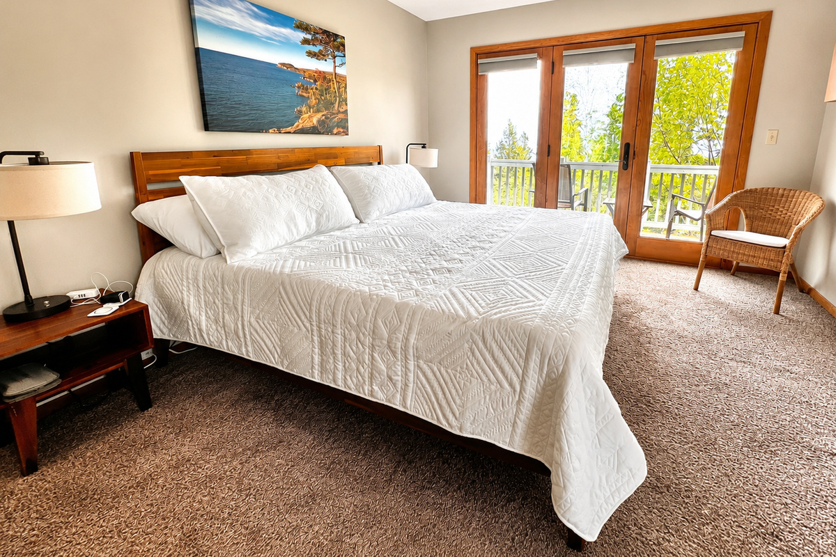 Serene primary bedroom upstairs featuring a plush king bed, large windows with breathtaking Lake Superior views, and access to a private deck. This tranquil retreat offers the perfect blend of comfort and natural beauty.