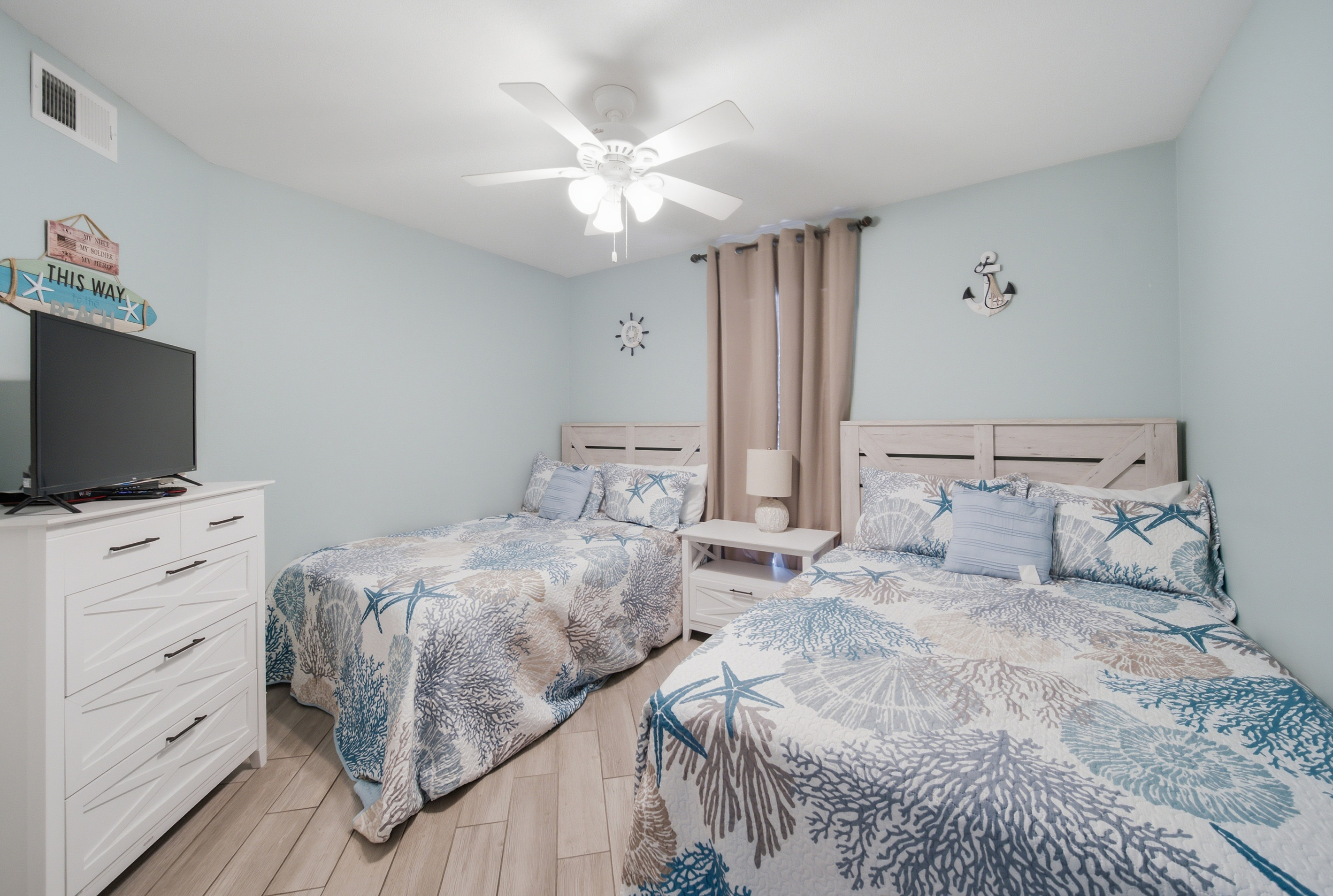 Wide view of the second bedroom's two full beds and dresser