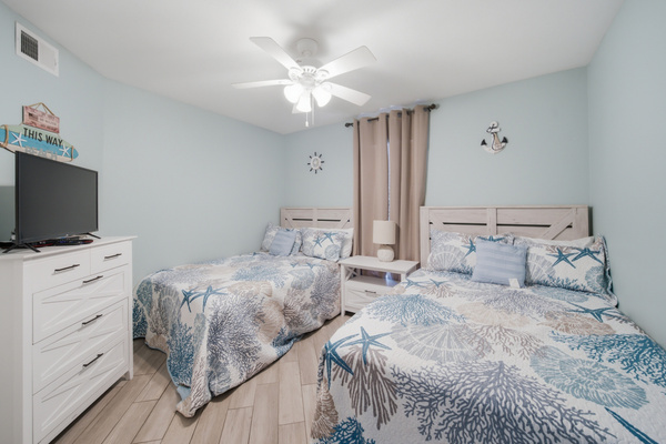 Wide view of the second bedroom's two full beds and dresser
