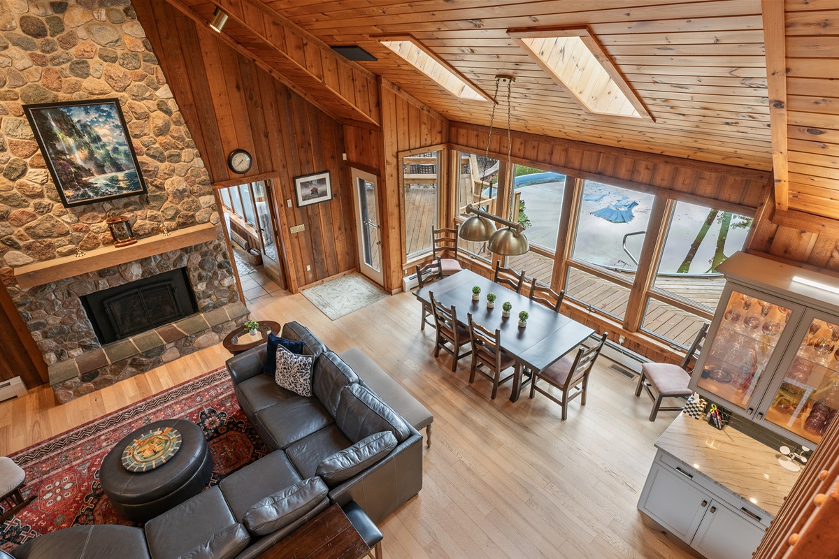 Grand living room with cathedral ceilings, wood finishes, and stunning forest views through the wall of windows.