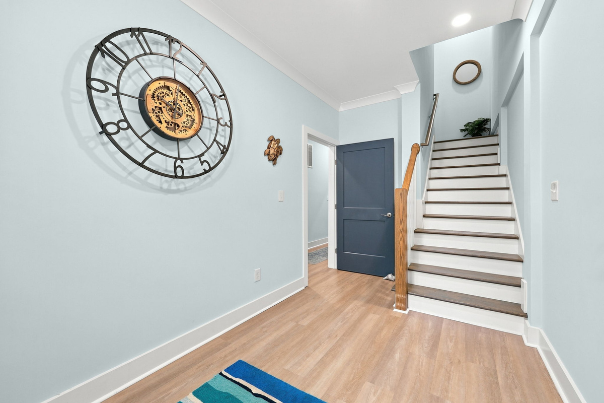 Welcoming entryway featuring coastal-inspired decor, a spacious layout, and staircase access to the upper levels
