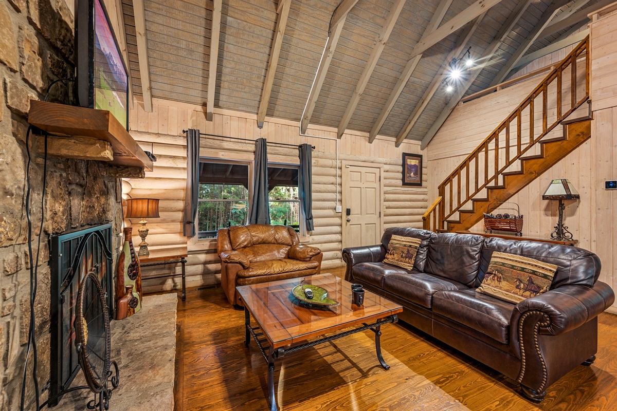 Inviting cabin living room with stone fireplace & comfortable leather seating.