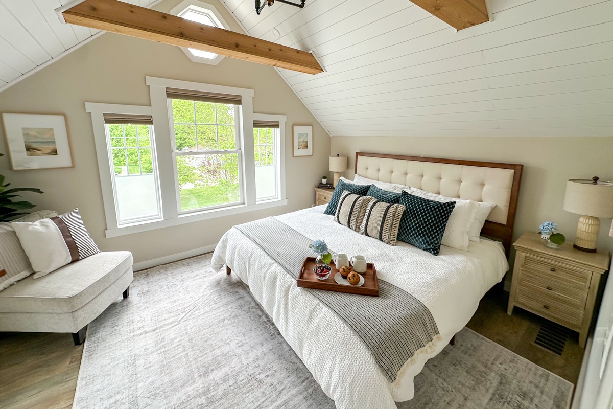 Unwind in timeless elegance in our vintage-inspired master bedroom. Shiplap ceilings, exposed beams and the warm glow of Edison blub lighting create a cozy charm. Featuring crisp white bedding for a clean, relaxing stay! 