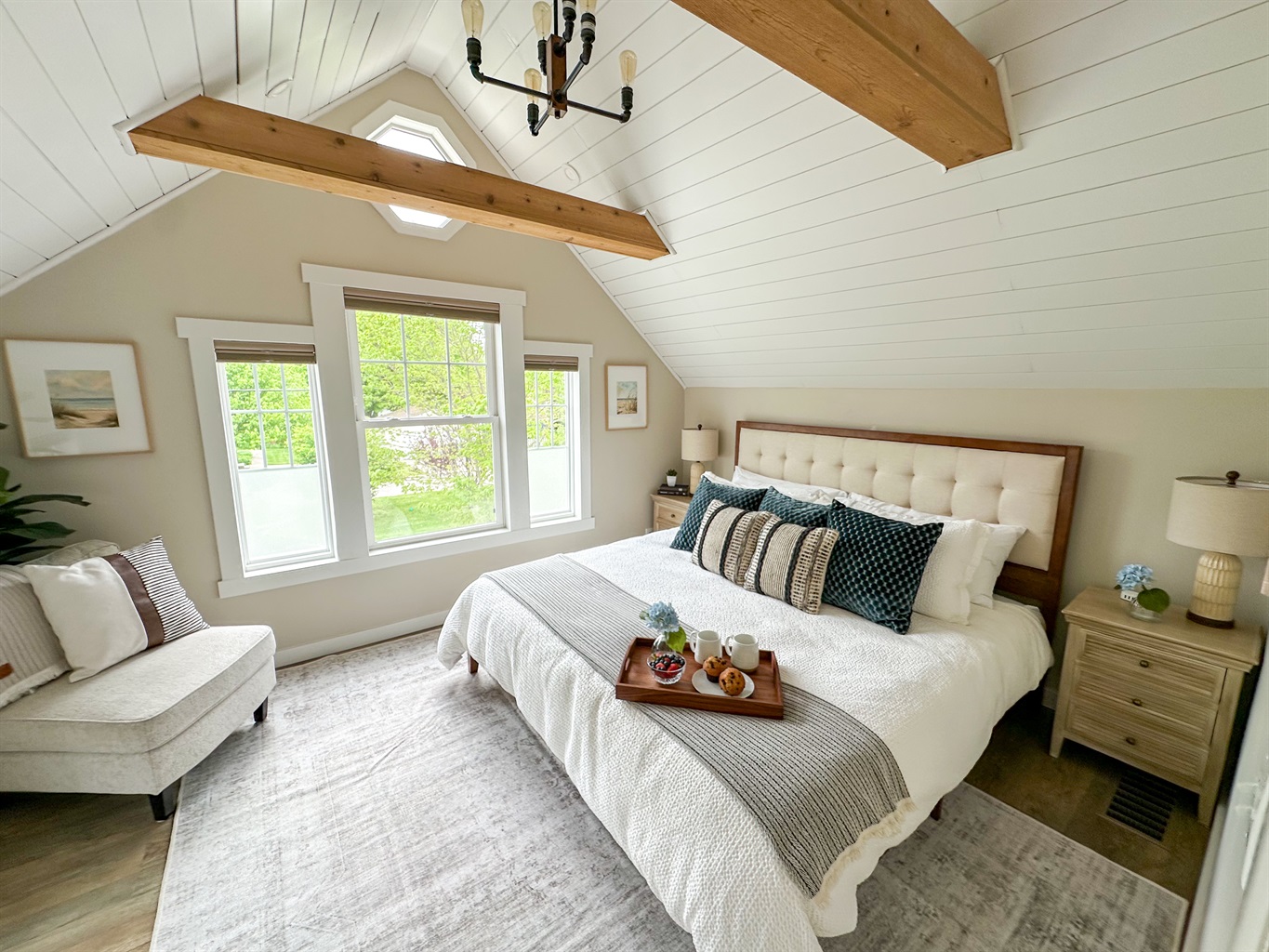 Unwind in timeless elegance in our vintage-inspired master bedroom. Shiplap ceilings, exposed beams and the warm glow of Edison blub lighting create a cozy charm. Featuring crisp white bedding for a clean, relaxing stay! 