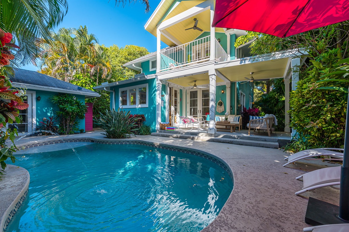Step into your private tropical oasis featuring a heated pool, sun loungers, an outdoor shower, and a romantic string-lit cabana. Enjoy relaxing or entertaining under the covered patio with comfortable seating and dining, and magnificent pool views.