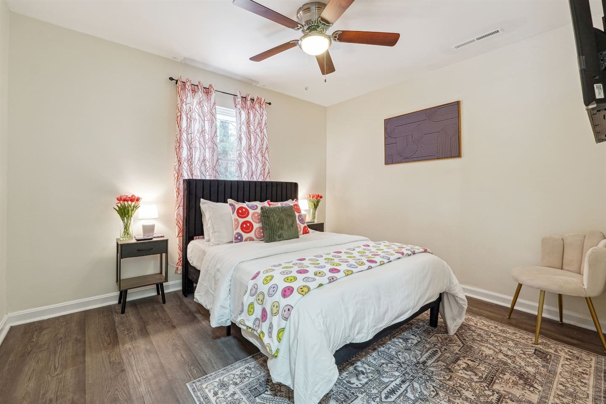 A comfortable bedroom featuring a bed, a ceiling fan, a window, a TV, and a closet — a cozy space to rest and relax.
