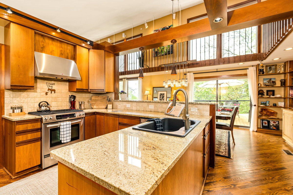 Fully equipped chef's kitchen with a gas stove, stone peninsula, and two-story windows. Open to the dining area to easily connect with family. Enjoy local Abingdon Olive Oil options.
