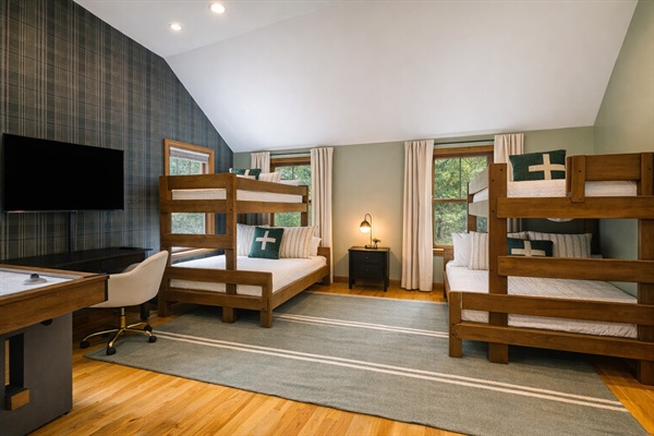 Eight people sleep here without a single argument about who gets a bed — two full-over-full bunk sets, a flat-screen TV, and enough floor space to claim your territory.