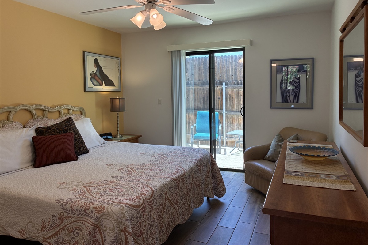 Bedroom with sliding glass door leading to fenced in backyard.