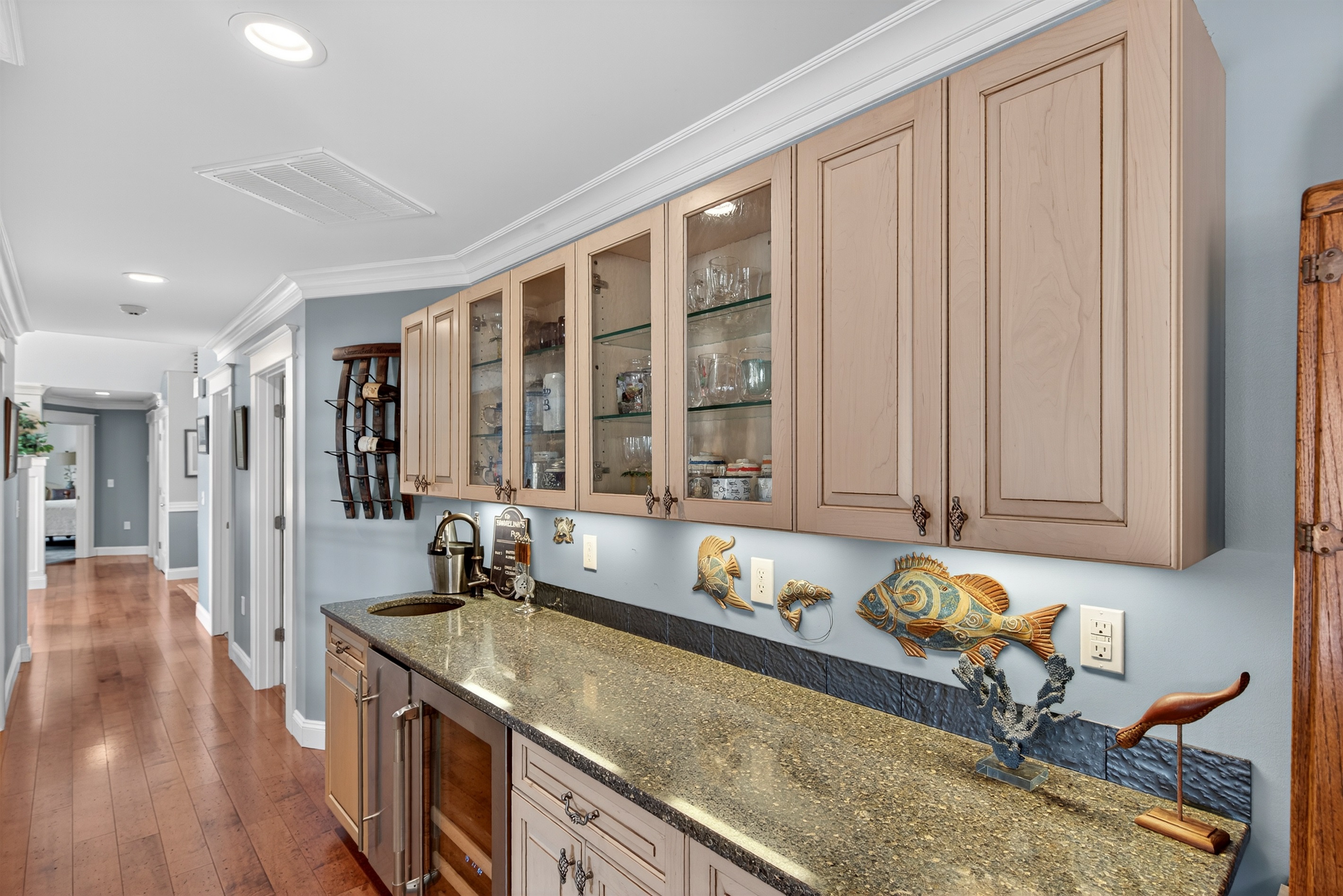 Enjoy a full wet bar setup featuring glass-front cabinetry, an ice maker, and beverage fridge.