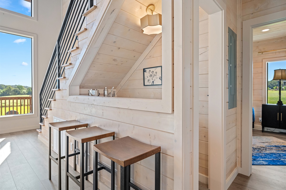 Breakfast bar nook with modern stools tucked under the staircase.