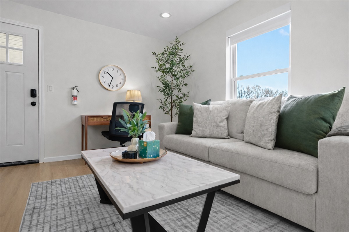 Bright, inviting living room with plush seating, natural light, and a dedicated workspace—perfect for relaxing, working, or enjoying a cozy night in.
