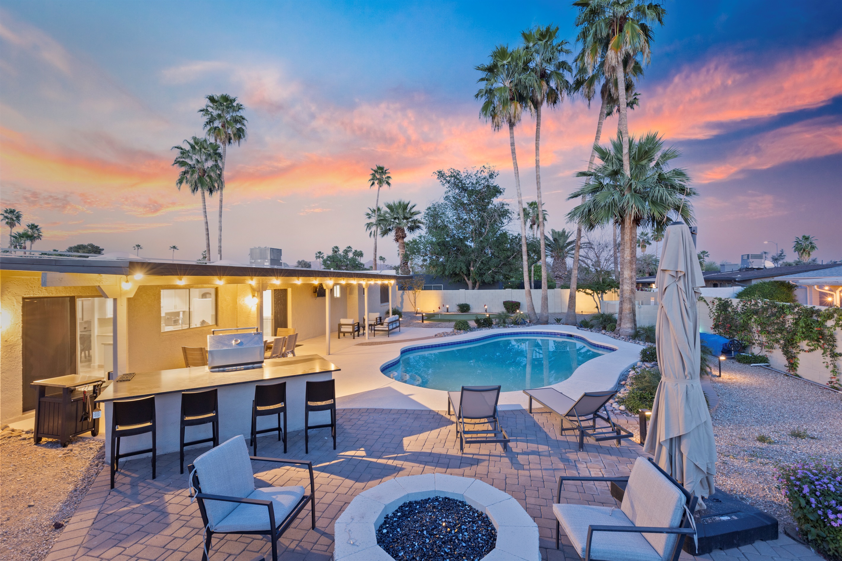 Private backyard with pool, spa, outdoor TV, BBQ, Putting Green, Corn Hole and multiple areas for dining and seating.