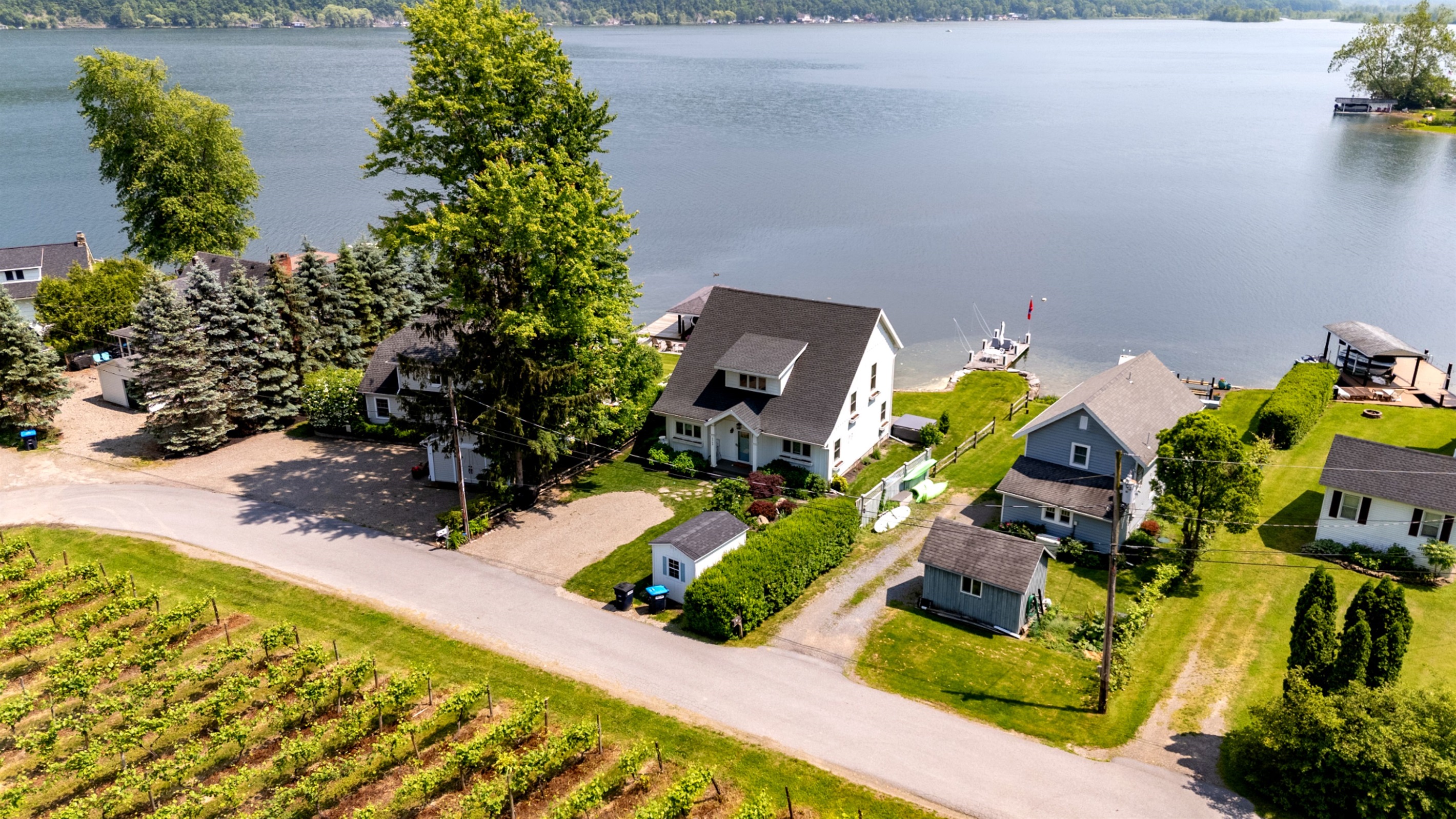 Stunning aerial view of a serene Finger Lakes waterfront retreat, complete with private dock, lush greenery, and charming lakefront homes—perfect for peaceful getaways and water adventures