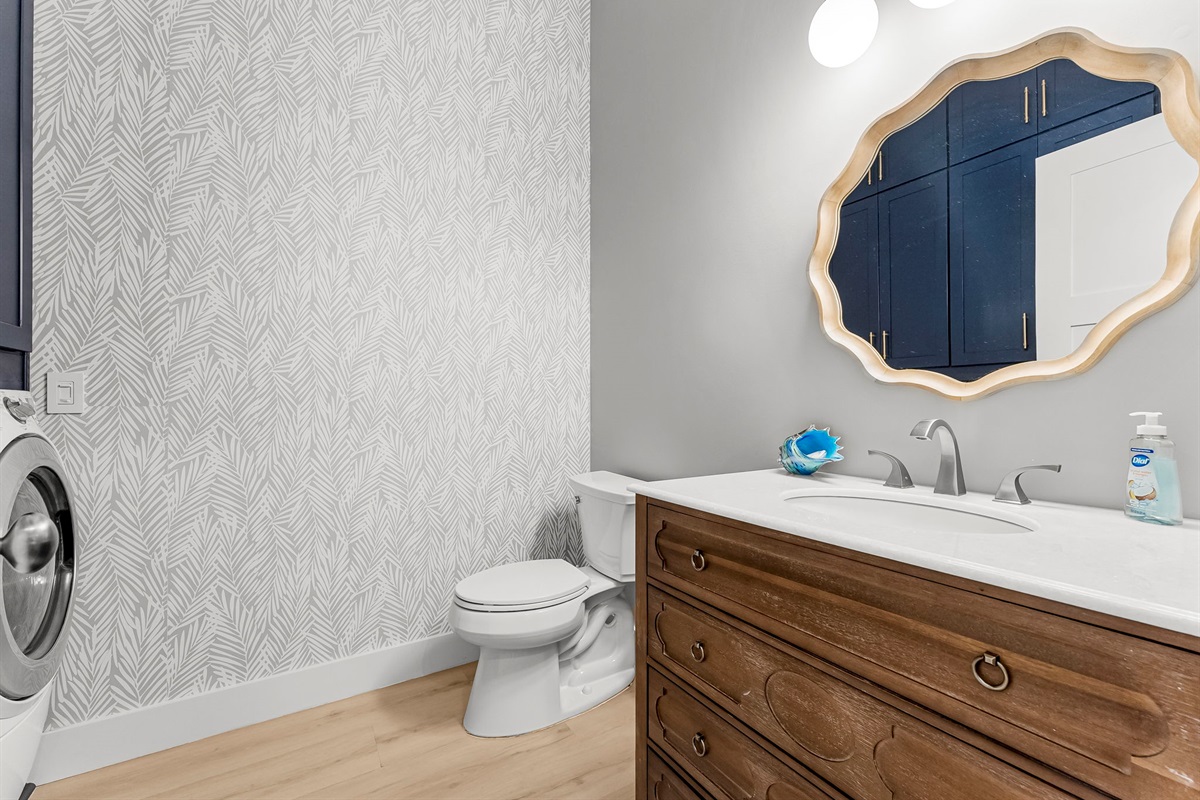 Convenient half bath paired with a full-size washer & dryer and custom ceiling-to-floor cabinets complete with all your laundry essentials.