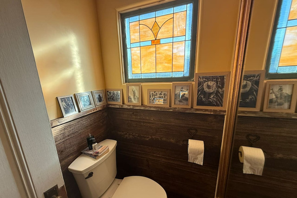 The second powder room with a matching stain glass window, ranch fencing paneling, and plaster walls. 