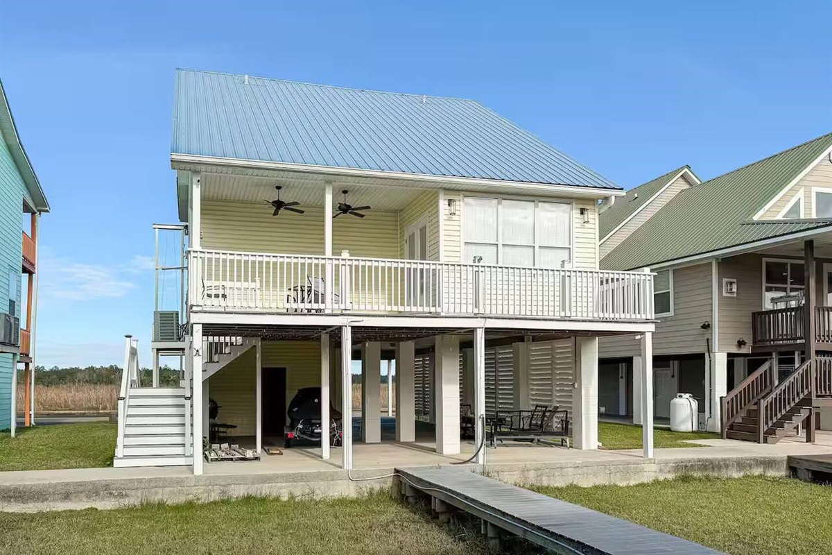 Beautiful raised beach house featuring wide porches, shaded ground-level space, and easy outdoor access.