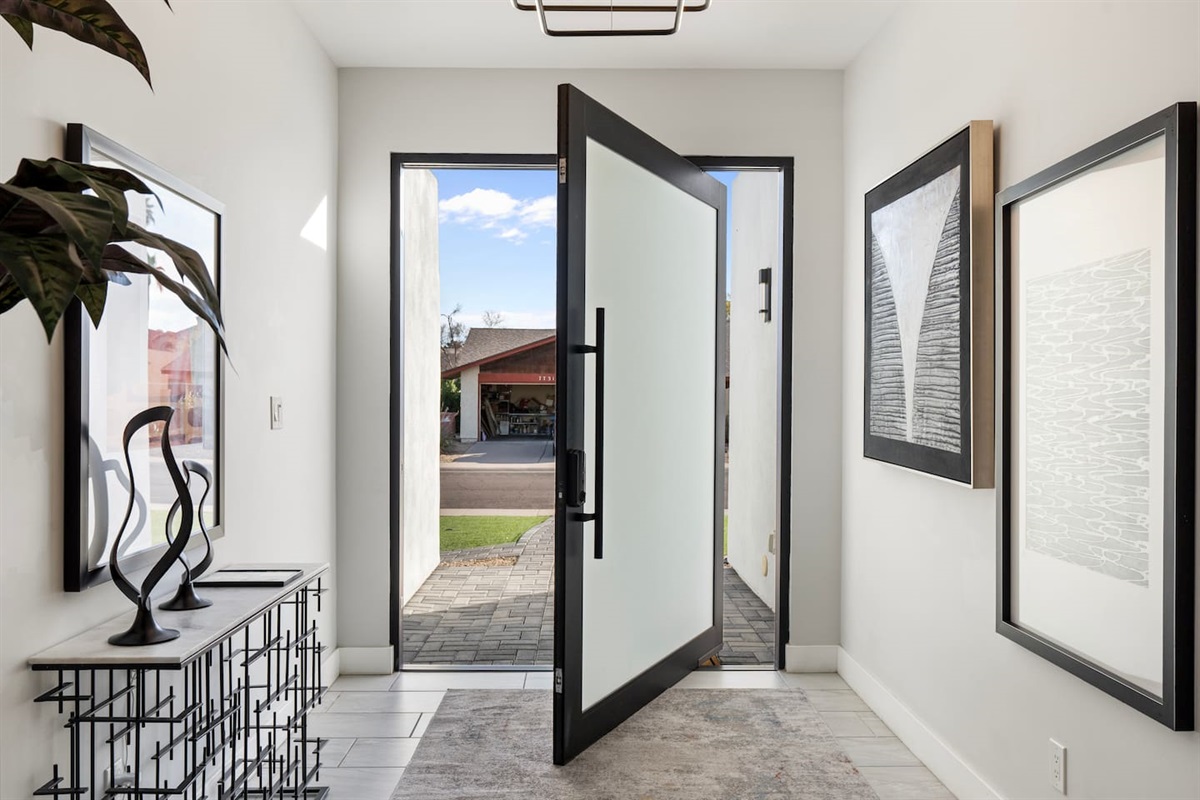 Step through the sleek black-framed pivot door and into a space that sets the tone for style and sophistication.