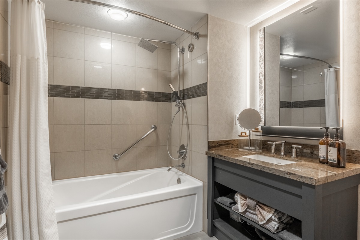 The bathroom features clean white tile, a tub/shower combo, and a modern layout designed for comfort and ease.