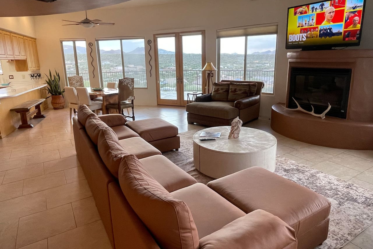 Settle into the spacious living room with comfortable seating, a fireplace, TV, and large windows that fill the space with natural light.
