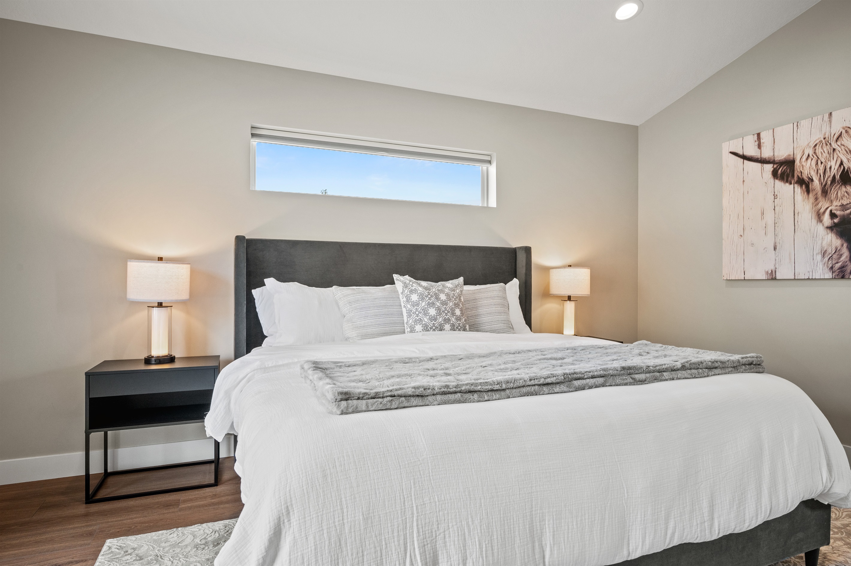 Spacious king bedroom with ensuite, recessed lighting, and window.