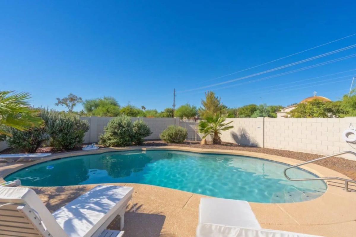 Sparkling pool oasis with mature landscaping, lounge area, and resort-style backyard retreat.