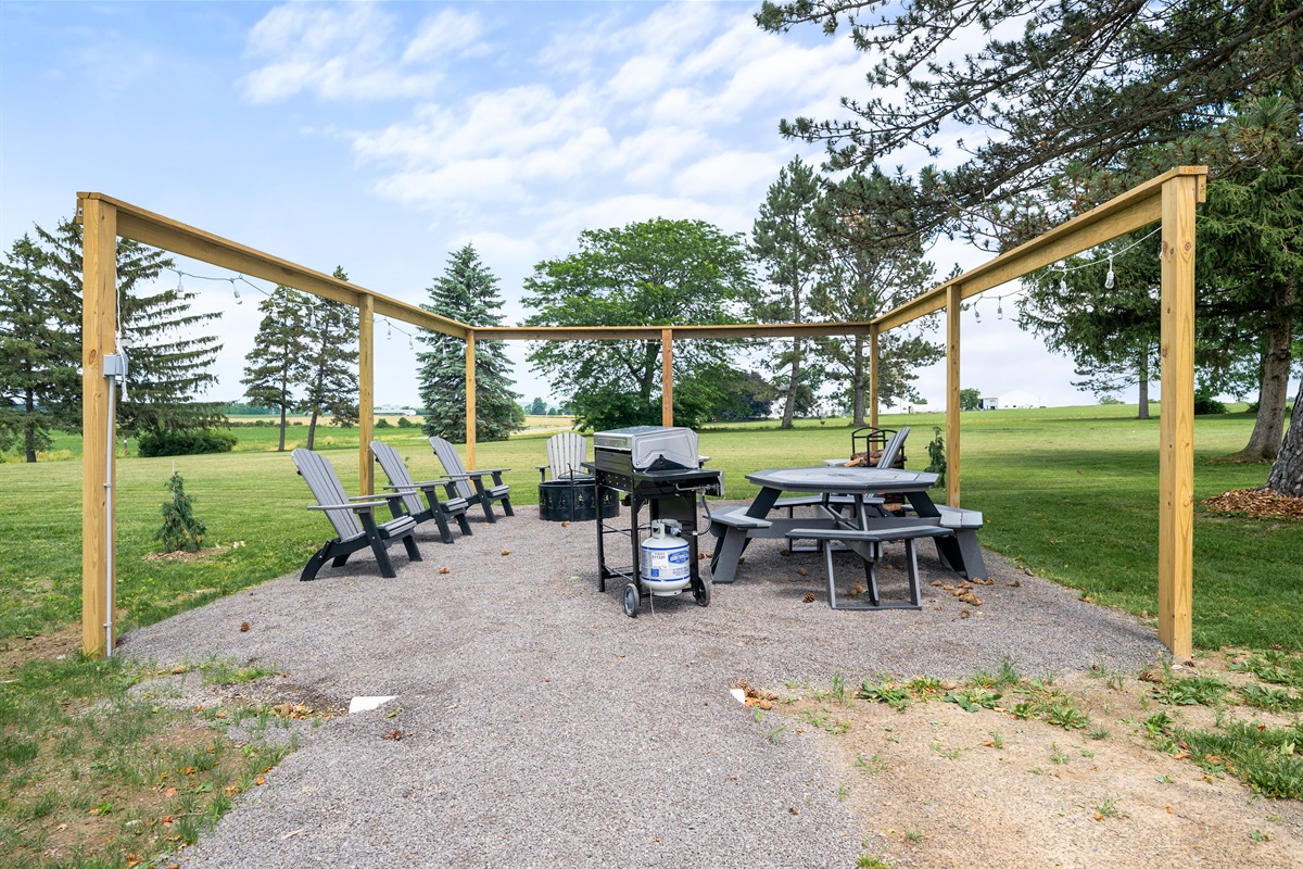 Expansive patio area with Adirondack chairs, picnic tables, and string lights—ideal for entertaining