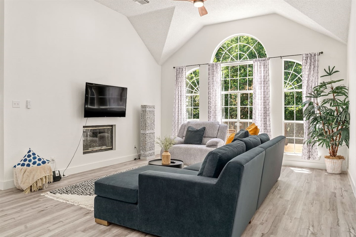 Modern open-concept living area with TV, plush seating and natural light.