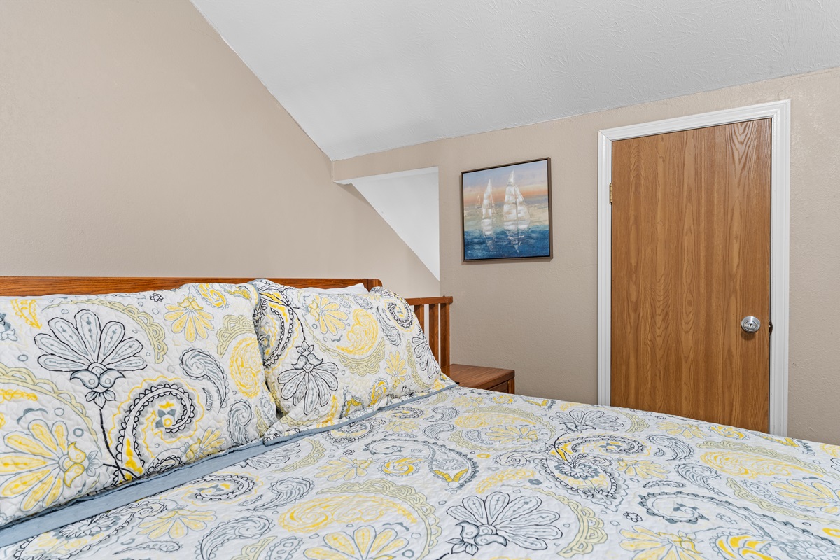 A closer look at the upstairs queen bed tucked beneath the vaulted ceiling.