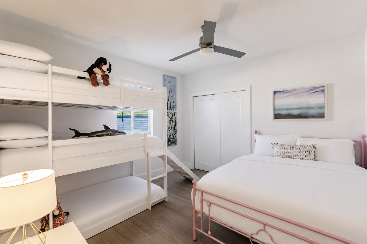 Coastal inspired kids room with triple bunks, a slide and a queen bed