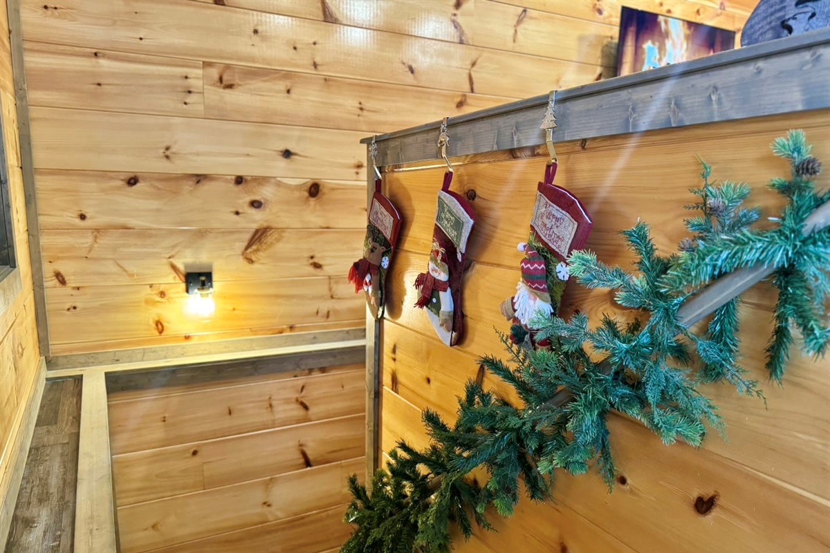 Walk down the cozy staircase trimmed with stockings and pine, where the glow of the fire invites you to settle in and let the holiday magic linger a little longer.