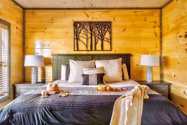 Snuggle up in bed overlooking the peaceful woods after a long day of sightseeing—complete with cozy linens, plush pillows, and the gentle glow of bedside lamps for the perfect mountain retreat.