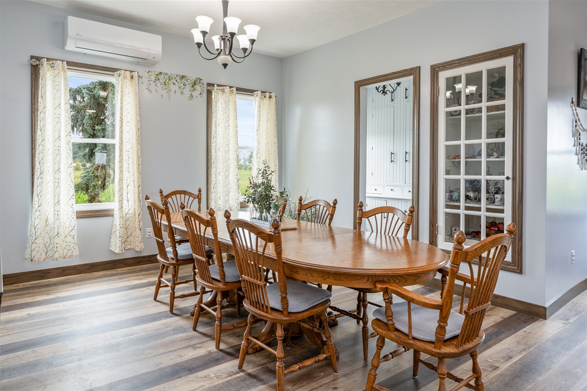 Bright and airy dining space featuring large windows, elegant curtains, and a spacious wooden table perfect for family meals or gatherings.