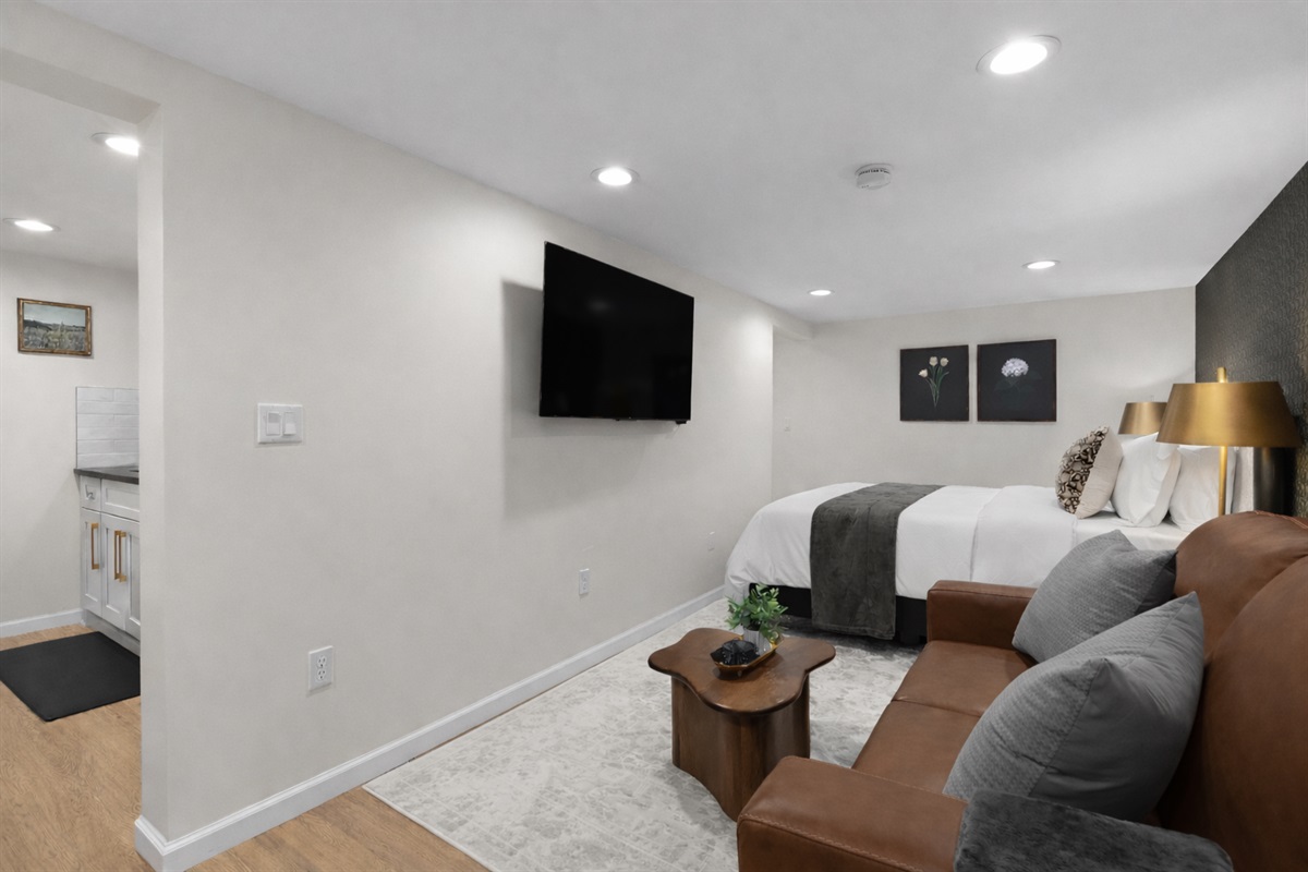 Inviting studio-style layout with a plush bed, cozy seating, and wall-mounted TV—designed for comfort, relaxation, and an easy, enjoyable stay.