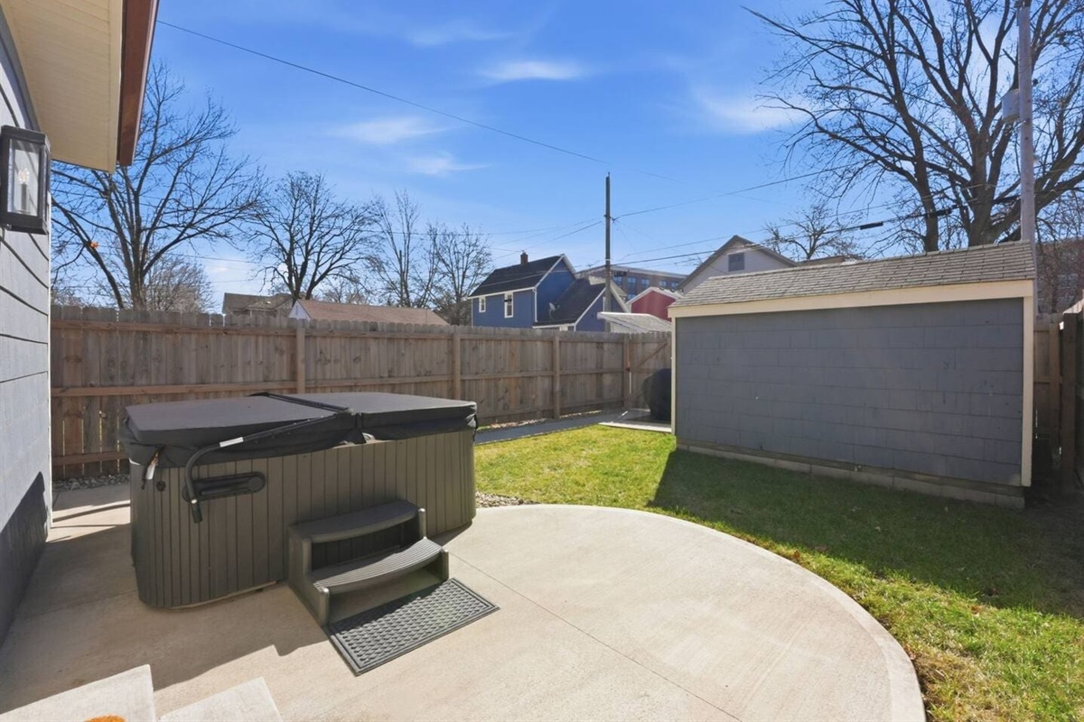 Spacious fenced yard with hot tub and patio area for relaxing and enjoying the outdoors