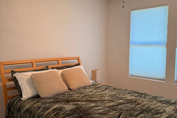 Queen bedroom with dresser storage, ceiling fan, and natural light for a comfortable stay.