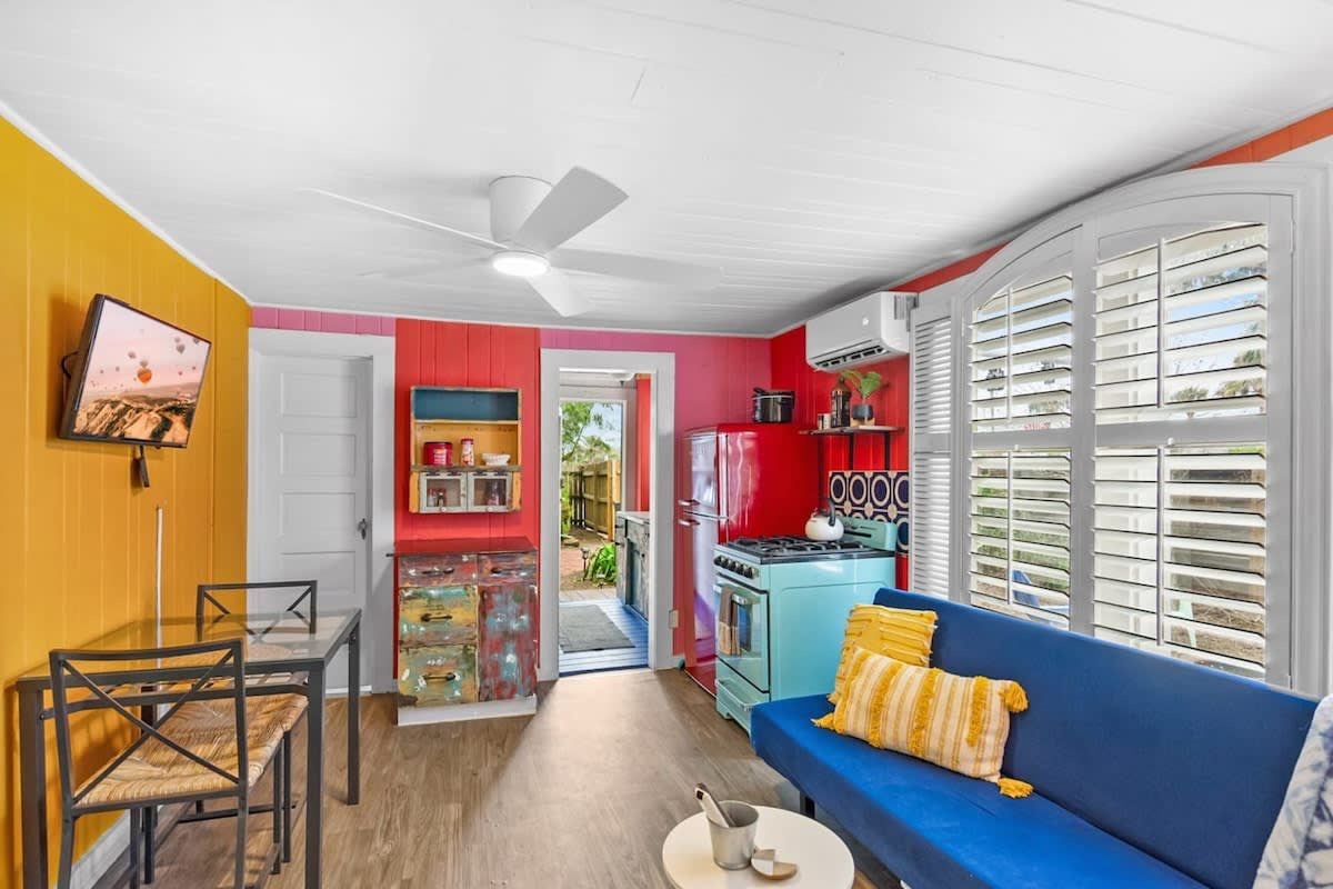 Tangerine, cobalt and pink, all at once, and somehow it works beautifully. This is the open heart of the cottage, where the sitting area, the dining table and the kitchen all share one bright and cheerful room.