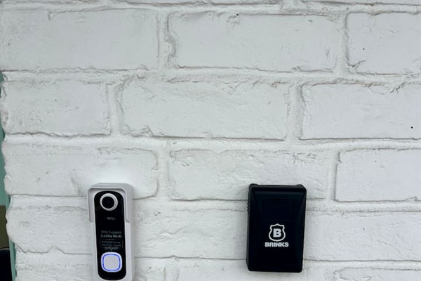 Entry detail with doorbell camera and Brinks access panel beside the front door.

