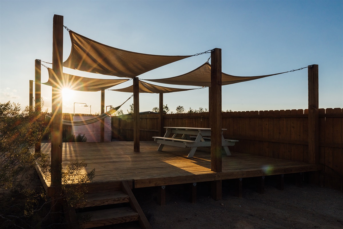 Sunset over the outdoor deck with picnic table and hammock, glowing desert skies, and peaceful Joshua Tree scenery.