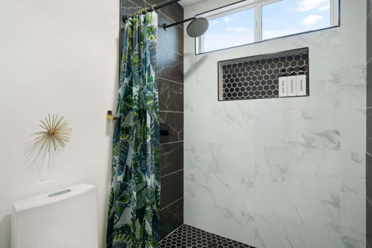 Bright bathroom with marble tile, walk-in shower, decorative accents, and modern fixtures.