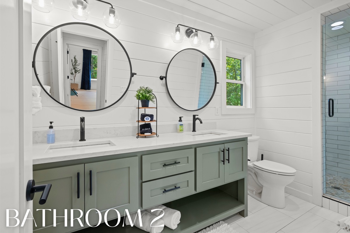 Bathroom 2 with dual sinks and glass shower.