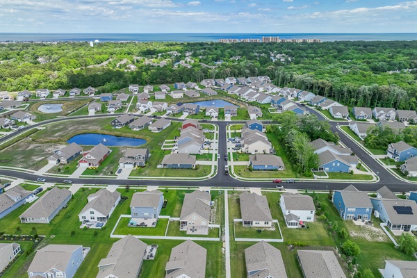 Aerial view of Ocean View Beach Club North: tranquil community ponds, tree-lined streets, and coastal greenery, with the Atlantic horizon in the distance.