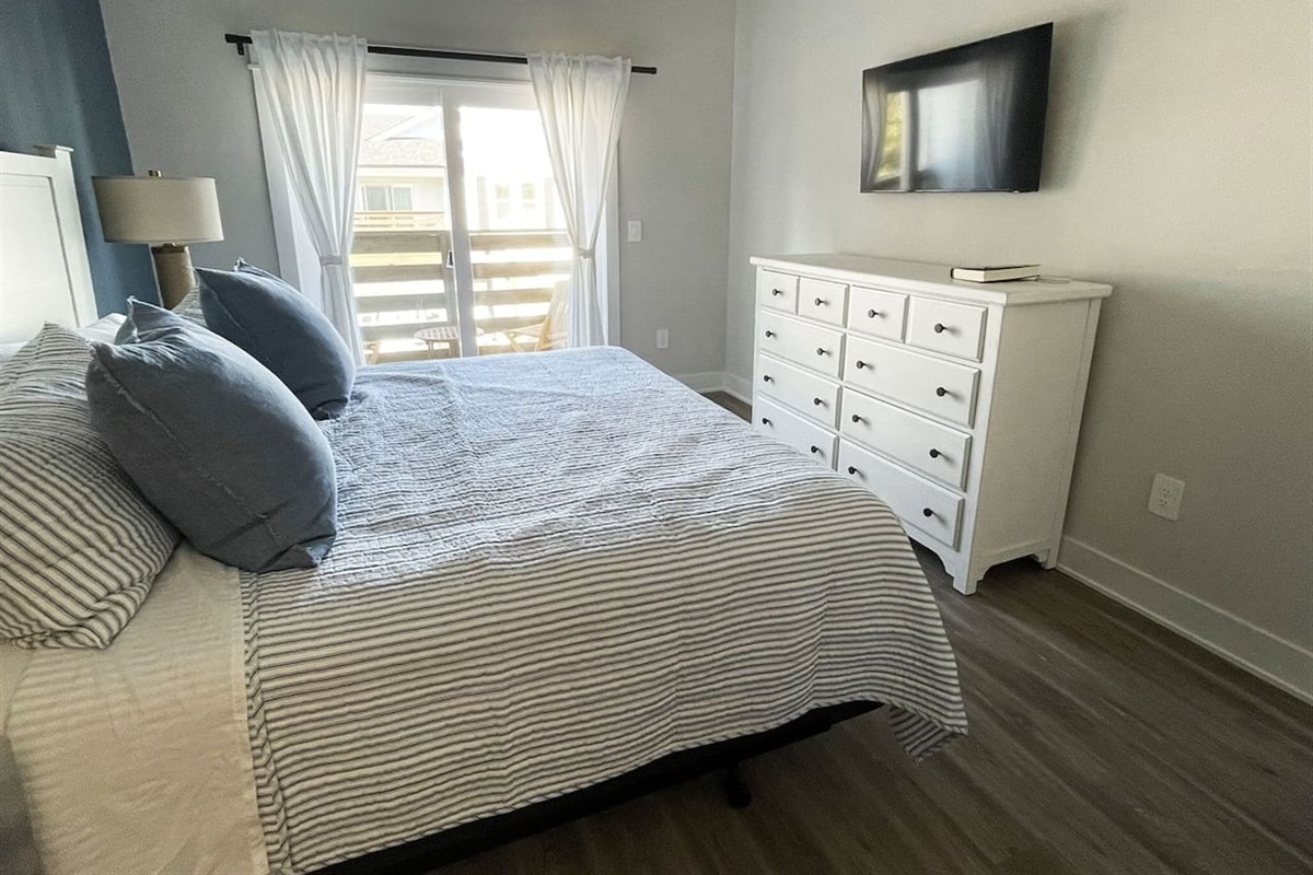 Another look at the serene primary bedroom showcasing ample storage, natural light, and wall-mounted TV for added comfort.