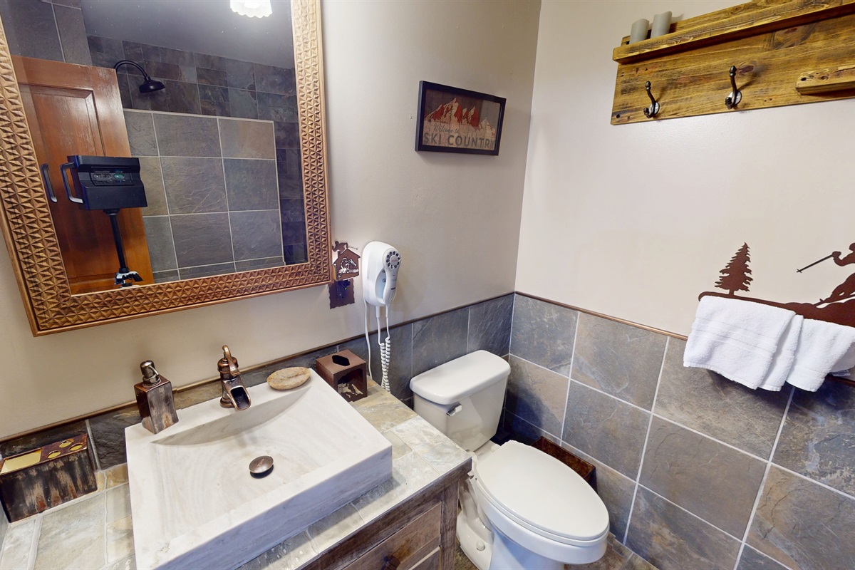 Mountain-chic bathroom with rustic stone tiles and modern fixtures — unwind after a day on the slopes.