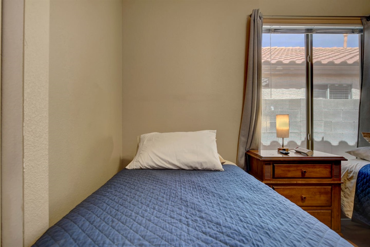 Bright twin room with blue bedding, window, and bedside lamp