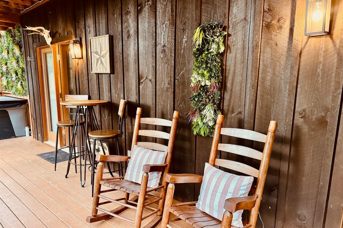 Cozy porch with rocking chairs, bistro table, and greenery wreath.