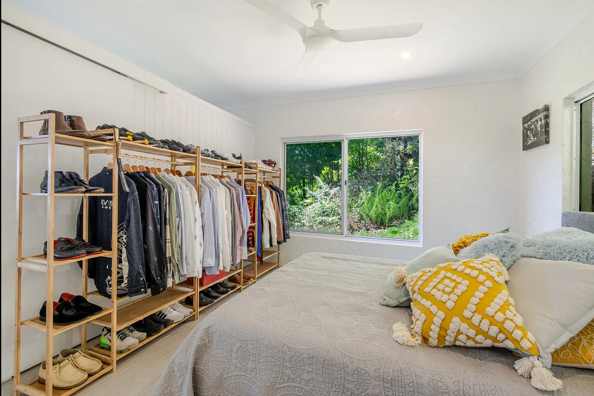 A comfortable bedroom with ceiling fan, natural light and generous open wardrobe space for longer stays at Nicos Butterfly Beach House.