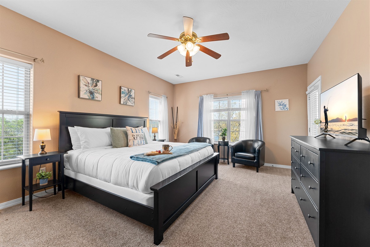 Spacious primary bedroom with a king bed, smart tv, view of the lake and attached ensuite bathroom